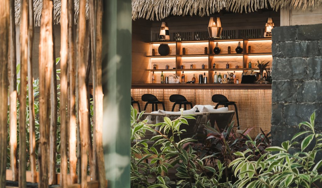 View of the thatched-roof bar through tropical foliage at Bom Bom Beach Club
