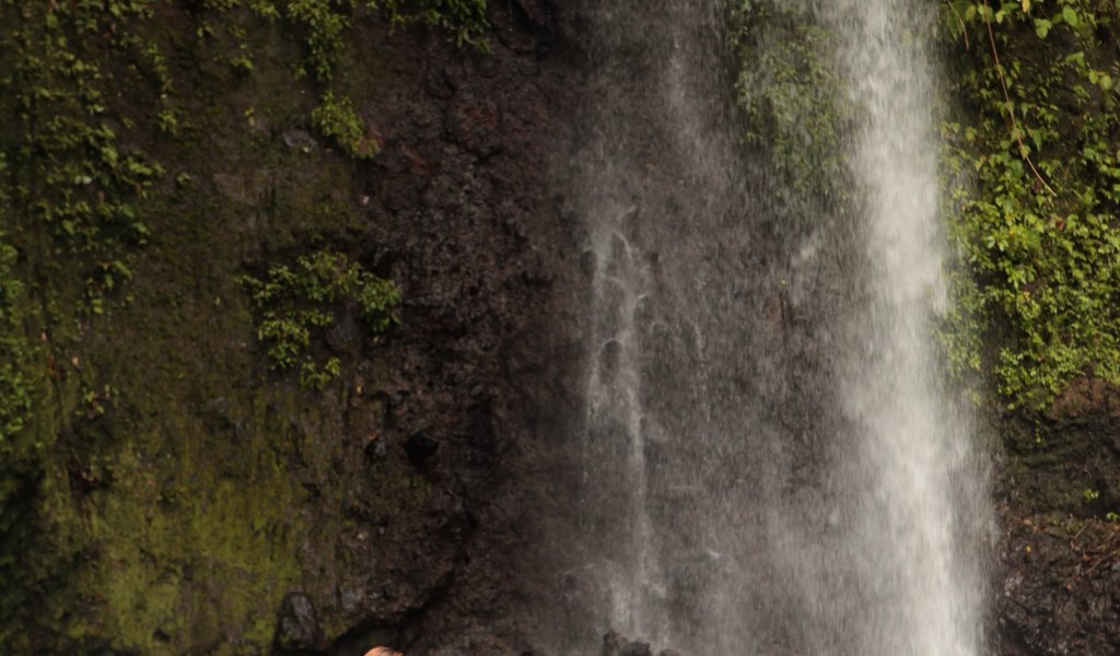 Family standing near the São Nicolau Waterfall in São Tomé, enjoying the view