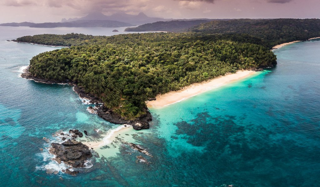 Aerial view of Príncipe Island, with crystal-clear water and dense rainforest vegetation.