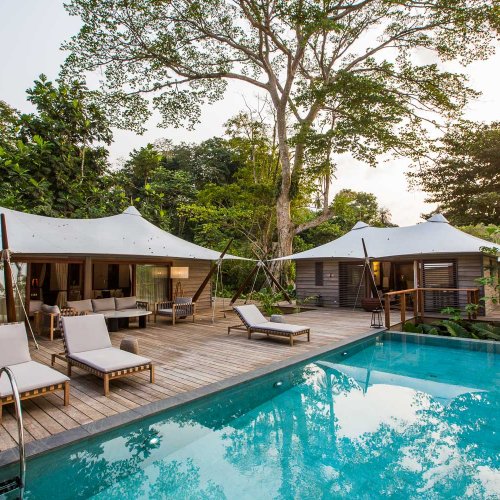 Pool with three loungers and in the background the three bedroom villa at Sundy Praia