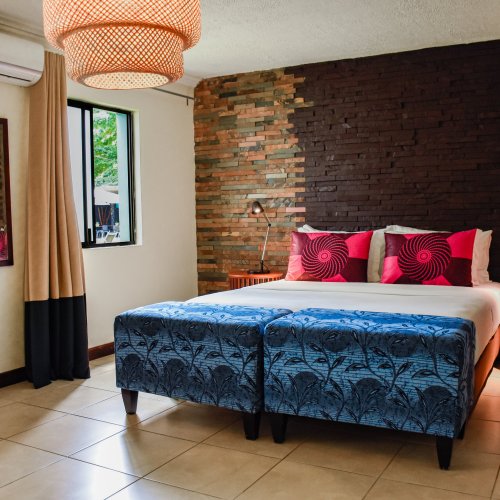 Bedroom with red cushions and stone wall at Omali