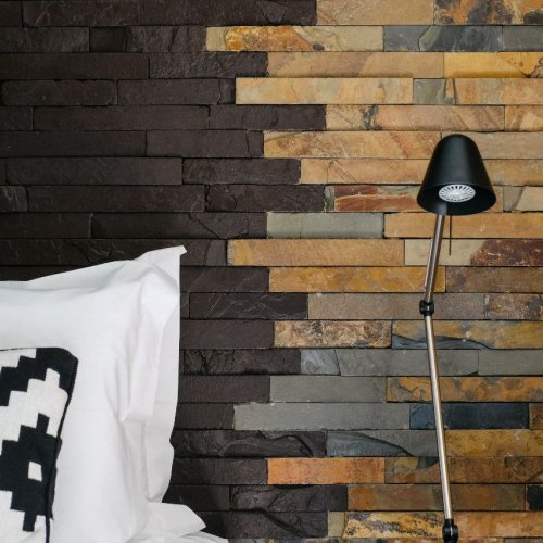 Bed with a patterned cushion and a stone wall background