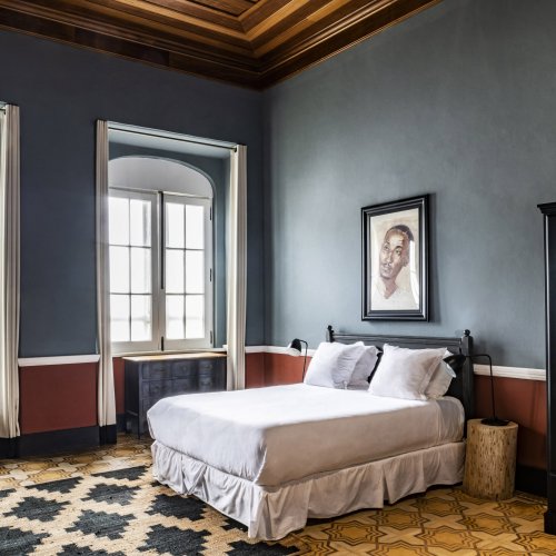Spacious bedroom with large windows and vintage design at Roça Sundy Boutique Hotel.