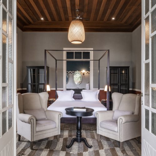 Spacious suite at Eclipse House in Roça Sundy with a four-poster bed, armchairs, and wooden ceiling