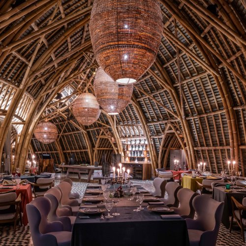 Interior view of OKA Sundy restaurant featuring bamboo architecture, decorative lighting, and dining tables