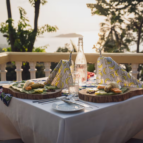 Terrace dining at Belo Monte at sunset, island views and tasting plates served on wooden boards.