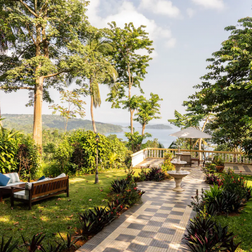 Garden terrace at Belo Monte with checkerboard path, fountain and lounge seating, overlooking the bay on Príncipe Island.