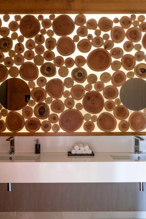 Casa de banho com dois lavatórios toalhas brancas enroladas ao centro parede de madeira atrás at Sundy Praia