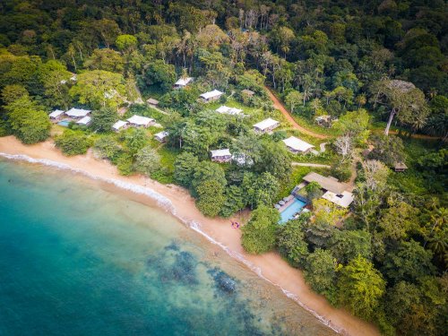 Vista aérea do mar, da praia e das pequenas cabanas na floresta verde at Sundy Praia