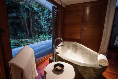 Granite bathtub at Sundy Praia with a view of the lush vegetation outside.