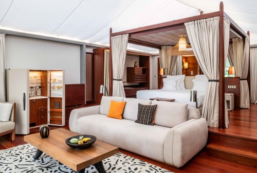 Room with carpet, small table, white couch, and slightly raised four-poster bed at Sundy Praia
