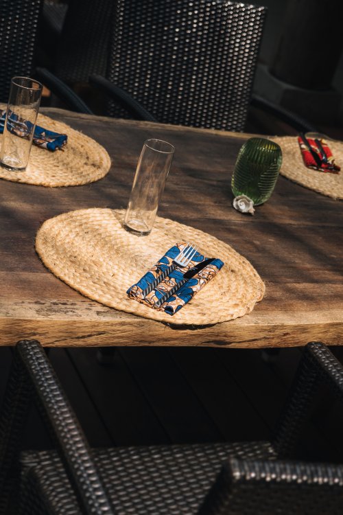Mesa posta com individuais de palha e guardanapos batik no Bom Bom Beach Club