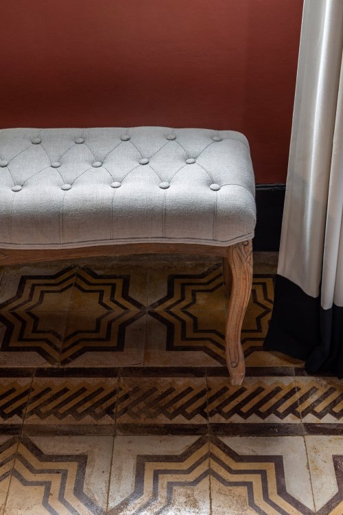 Close-up of a tufted bench and decorative patterned tiles at Roça Sundy