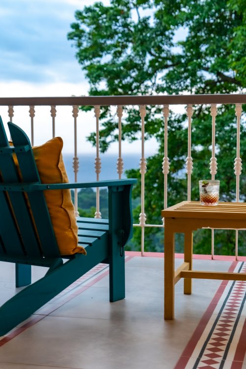 Glass of a refreshing drink on a balcony with ocean and forest views at Roça Sundy
