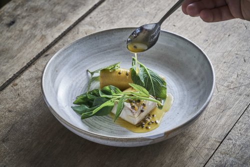 Prato de alta gastronomia apresentado numa mesa no restaurante OKA Sundy