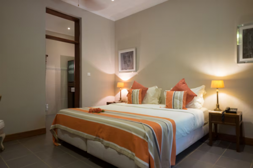 Quarto Jardim espaçoso com cama king, colcha às riscas e luz suave, porta para a casa de banho privativa.