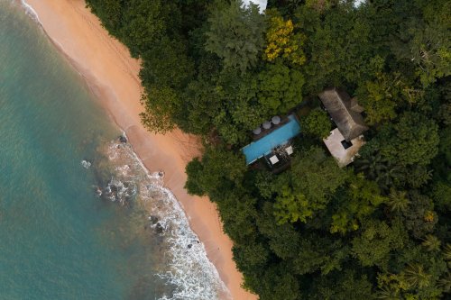 Aerial view of Sundy Praia beach and pool hidden in the forest on Príncipe Island, steps from the shoreline