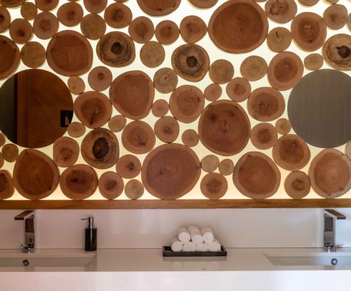 Bathroom with two sinks, rolled white towels in center, wall of wood behind at Sundy Praia