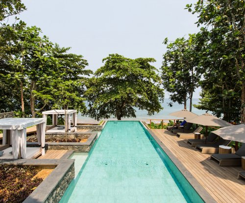 Long turquoise pool with loungers on both sides, sea in the background at Sundy Praia