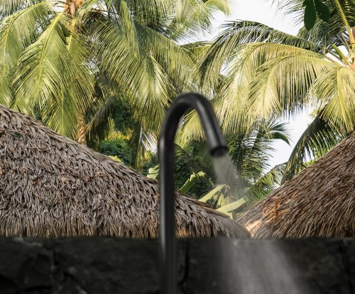 Outdoor shower with thatched roofs and palm trees at Bom Bom Beach Club