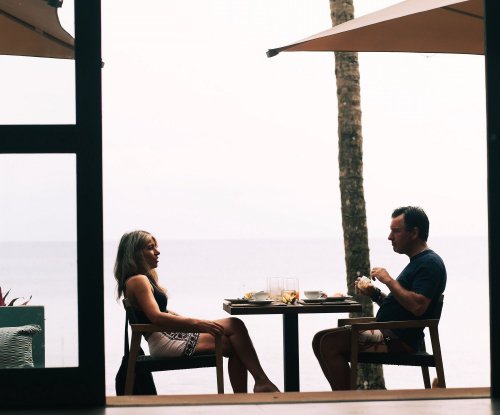 Two people sitting at an outdoor restaurant at Bom Bom Beach Resort with a hazy background
