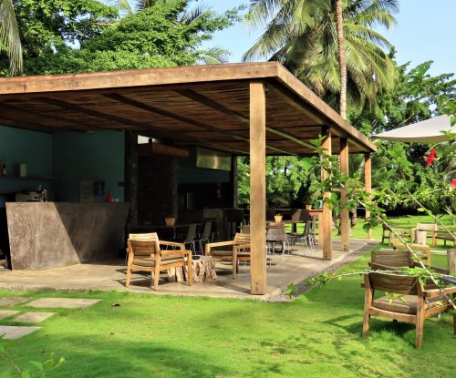 Outdoor bar and restaurant area with wooden chairs and lush greenery at Omali Hotel, São Tomé