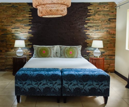 Quarto com otomanos azuis, parede de pedra e luminária de vime no Omali