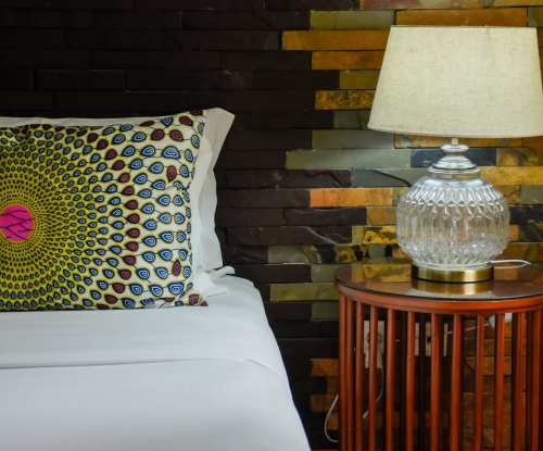 Bed with a patterned cushion and a vintage lamp at Omali