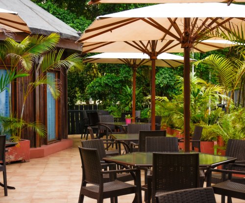 Outdoor dining area with tables, chairs, and umbrellas at Omali Restaurant, São Tomé