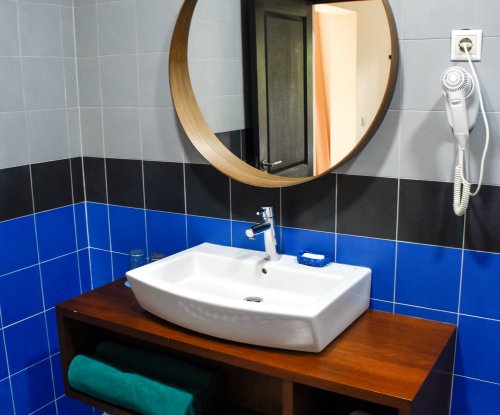 Banheiro com pia branca e espelho no Omali.