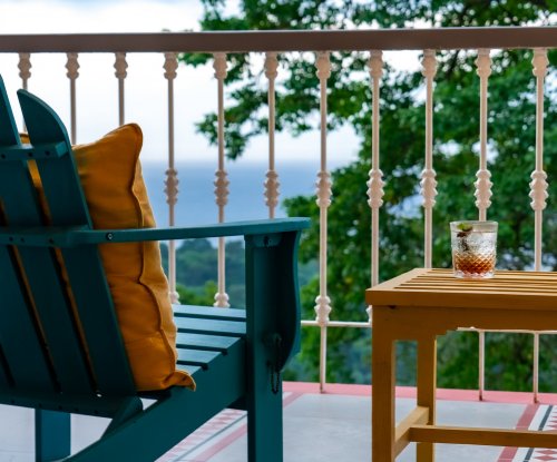Glass of a refreshing drink on a balcony with ocean and forest views at Roça Sundy