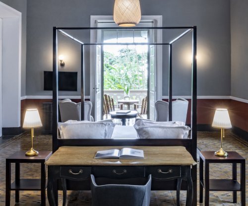 Spacious suite at Eclipse House in Roça Sundy with a four-poster bed, desk, and wooden ceiling