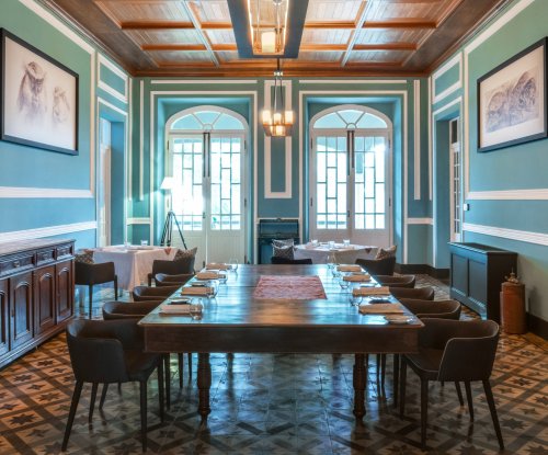 Elegant dining area at Roça Sundy with a long wooden table, art on the walls, and large windows
