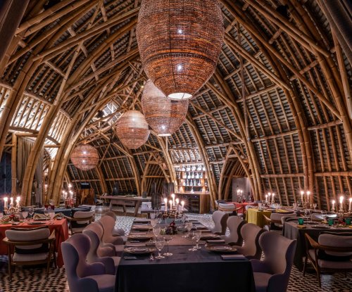 Vista interior do restaurante OKA Sundy com arquitetura de bambu, iluminação decorativa e mesas de jantar