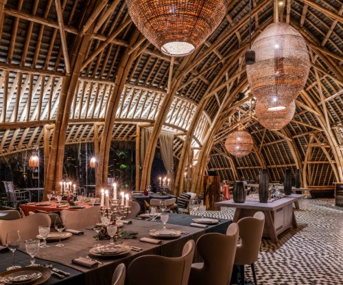 Vista interior do restaurante OKA Sundy com arquitetura de bambu, iluminação decorativa e mesas de jantar