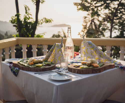 Terrace dining at Belo Monte at sunset, island views and tasting plates served on wooden boards.