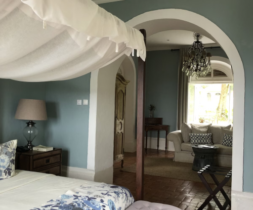 Panoramic Suite interior at Belo Monte, canopy bed and arched doorway leading to a separate lounge with chandelier.