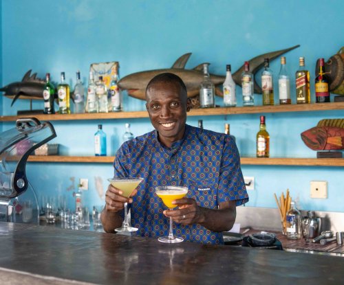 Bartender serving two tropical cocktails at the bar of Omali, São Tomé Island