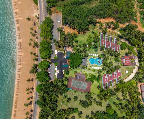 Aerial view of Omali hotel with swimming pool, tennis court and tropical gardens along the beachfront, São Tomé Island