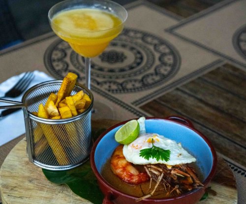 Prawn dish with fried egg, plantain chips and a tropical cocktail at the Omali restaurant, São Tomé Island