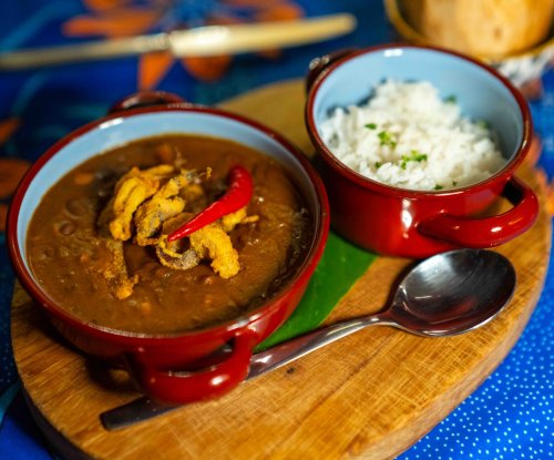 Traditional São Tomé stew with rice and red chilli served on a wooden board at the Omali restaurant, São Tomé Island