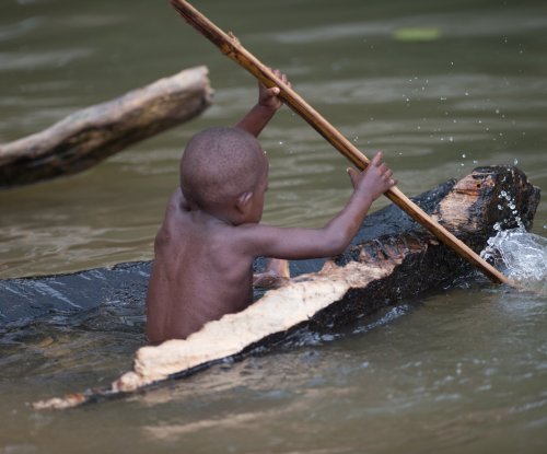 Criança a remar numa canoa de madeira artesanal no rio, Ilha do Príncipe