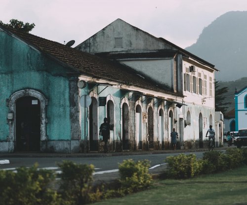 Colourful colonial buildings and blue church with a rocky peak in the background in Santo António, Príncipe Island
