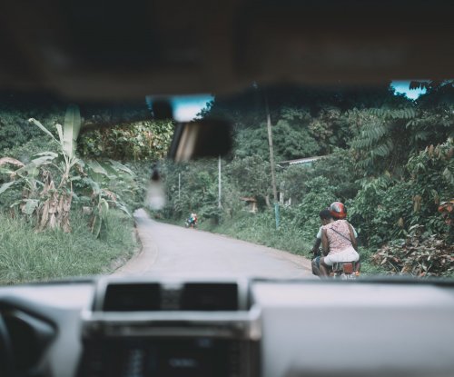 Tropical road seen from inside a car with a motorcyclist ahead, Príncipe Island