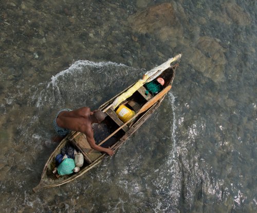 Overhead view of a fisherman in a wooden canoe with nets and fishing gear, Príncipe Island