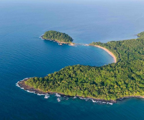 Vista aérea da costa nordeste com ilhéu coberto de vegetação e praia dourada, Ilha do Príncipe