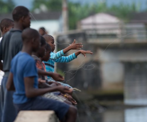 Children fishing with hand lines from the harbour wall in Santo António, Príncipe Island