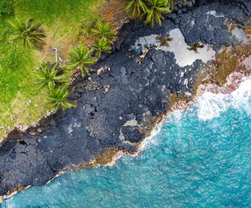 Vista aérea das rochas vulcânicas escuras junto ao oceano turquesa na Boca do Inferno, Ilha de São Tomé