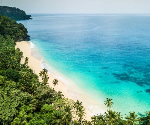 Areal view of a tropical empty beach with turquoise water and lush jungle behind