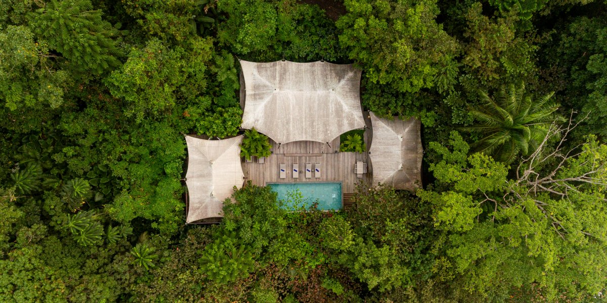 Vista aérea da Pool Villa de Sundy Praia com piscina privada e deck em madeira, integrada na floresta tropical, Ilha do Príncipe